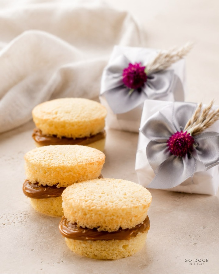 Little cakes filled with dulce de leche, beside two wrapped in fabric